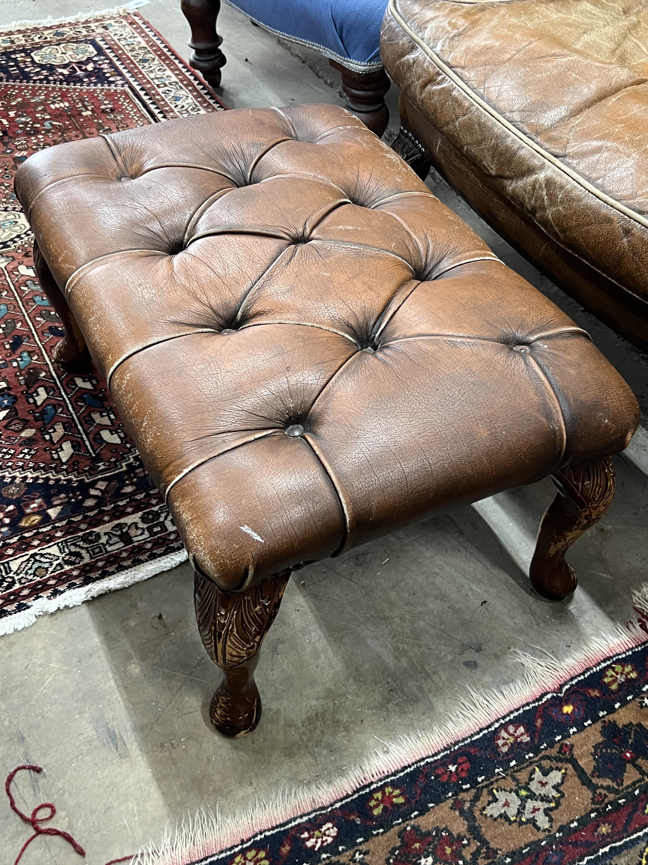 A Victorian style buttoned leather armchair, width 85cm, depth 76cm, height 106cm and a stool